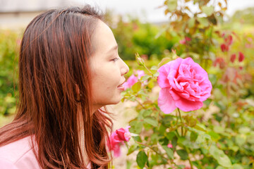 Fototapeta premium 薔薇の花の匂いを嗅ぐ日本人女性