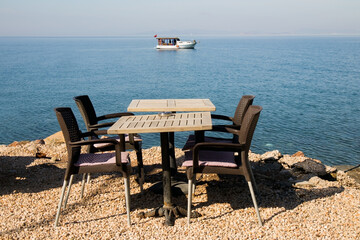 An empty table with four chairs by the blue sea
