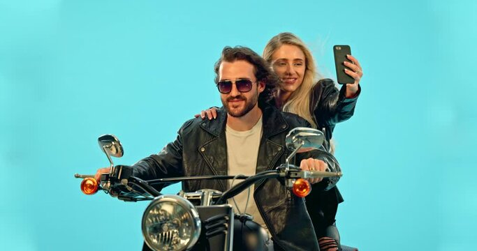 Selfie, smile and couple on motorcycle in studio for adventure, road trip and holiday mockup. Motorbike, transport and man and woman take picture for social media, post or memory on blue background