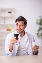 Young male chemist examining soft drink at the lab