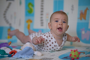 Portrait of a cute baby girl lying on the floor with toys.