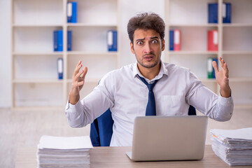 Young male employee and too much work in the office