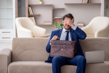 Obraz premium Young male employee working from home during pandemic