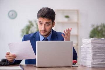 Young male employee and too much work in the office