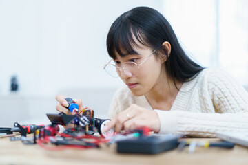 Happy cheerful Asian ethnicity female university student learning about robotic and programing by herself.