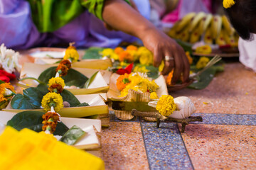 Hindu puja rituals being performed with flowers in front of priest during pooja, wedding, funeral ceremonies. Miscellaneous religious essentials are kept in front. A person is folding hands to worship - obrazy, fototapety, plakaty