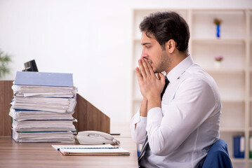 Naklejka premium Young male employee and too much work in the office