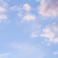 Blue sky background with pale pink clouds at sunset