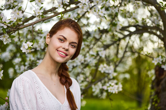 Beautiful young woman. model in white dress stands in white flowers. Horizontal photo. copy space.