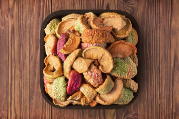 dried apples in square plate on wooden table background. vegetarian organic food for healthy diet.