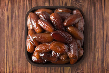 dried date fruit in square plate on wooden table background. vegetarian organic food for healthy...