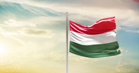 Hungary national flag waving in beautiful sky. The symbol of the state on wavy silk fabric.