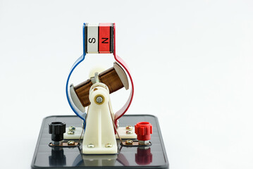 Experimental electric generator on white background, consists of copper coils and magnets. A...