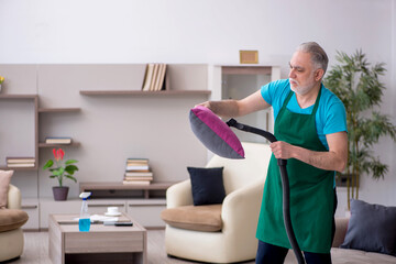 Old male contractor cleaning the house