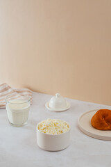 Fototapeta na wymiar cottage cheese in a bowl, a bun on a plate. milk in a glass