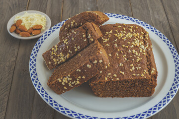 slices of chocolate sponge cake with keto diet almonds on a white ceramic plate on a wooden table