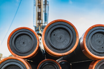 Pipes for a well close-up. Powerful drilling rig against a cloudy sky. Drilling of deep wells....