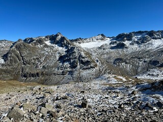 Fototapeta premium Rocky mountain peaks Piz Sarsura Pitschen (3132 m), Piz Sarsura (3176 m) and Grippa Naira (3130 m) in Albula Alps and above the alpine valley Val Grialetsch, Zernez - Canton of Grisons, Switzerland