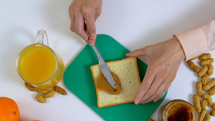 Woman hands preparing sandwitch with peanut butter on the kitchen, top view