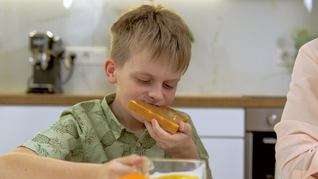 Boy drinking orange juice and eating sandwitch with peanut butter 