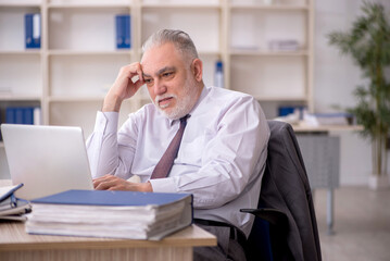 Fototapeta premium Old male employee working in the office