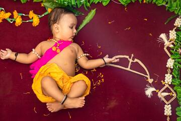 cute Indian boy dresses as lord rama with bow and flowers from top angle - obrazy, fototapety, plakaty