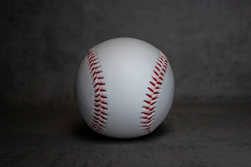 Close-up of a white baseball with red stitching on a grey background