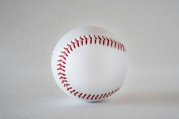 Close-up of a white baseball with red stitching on a grey background