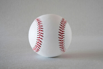 Close-up of a white baseball with red stitching on a grey background