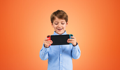 Smiling boy using handheld console, orange