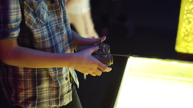 Teenage boy hands playing with game console in amusement center. kid having fun in entertainment park. childhood, leisure time and entertainment