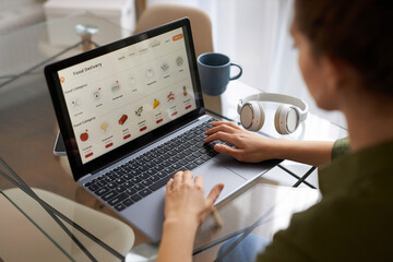 High angle view at young woman using online shopping website for grocery delivery, copy space