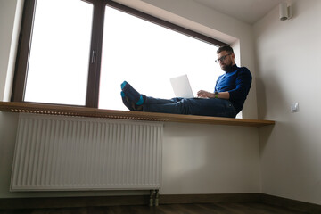 man in blue sweater and jeans is working alone at home with laptop