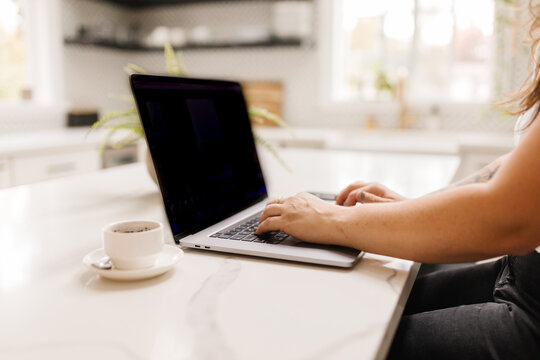 Side view of a woman working on computer with coffee inside