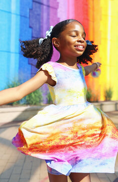 Young girl spinning in front of rainbow mural in Virginia
