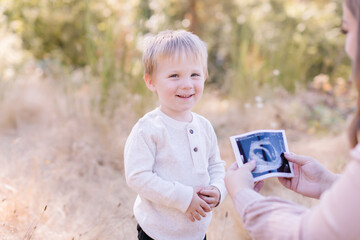 Mom showing twins ultrasound to happy toddler