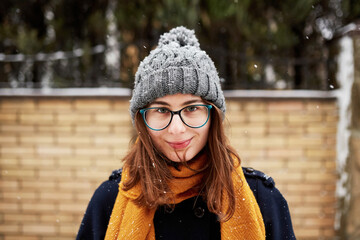 woman in yellow scarf and blue coat in middle of snowy street
