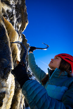 A woman with long hair ice climbing