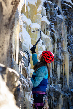 A woman with long hair ice climbing