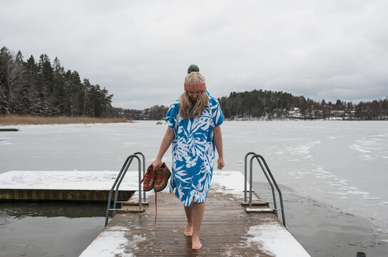 woman walking on a dock ready to go cold water swimming