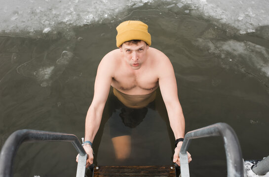 man swimming in frozen cold water in Sweden