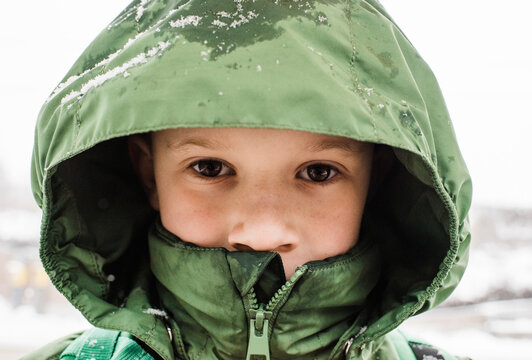 close up portrait of boy with his hood up in the snow