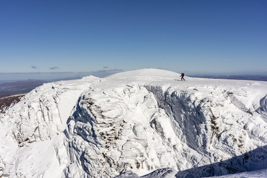 Backcountry Skier above snow-covered cliffs