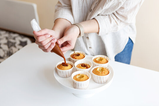 pastry chef girl prepares cupcakes with cream in the kitchen