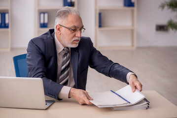 Old male employee working in the office