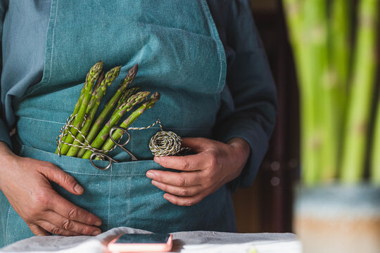 a woman in an apron will cook asparagus and reads a recipe