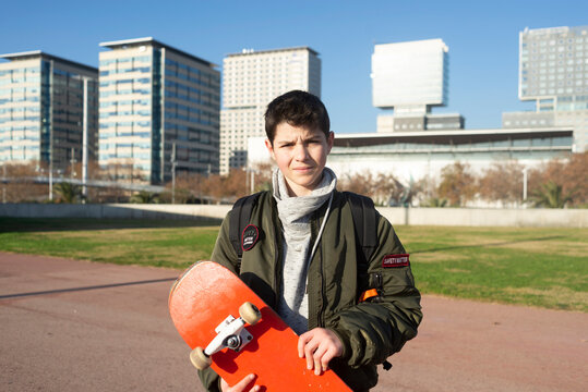 Shot of a young man holding a skateboard outside.