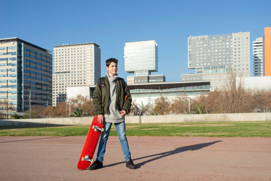 Shot of a young man holding a skateboard outside.