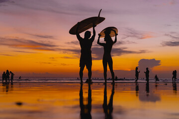 Surfers with surfboards at sunset, Bali.