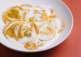 Boiled ravioli with sour cream on plate